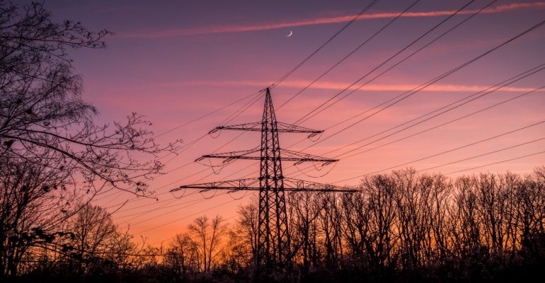 Silhouette of poles and power lines in the sunset